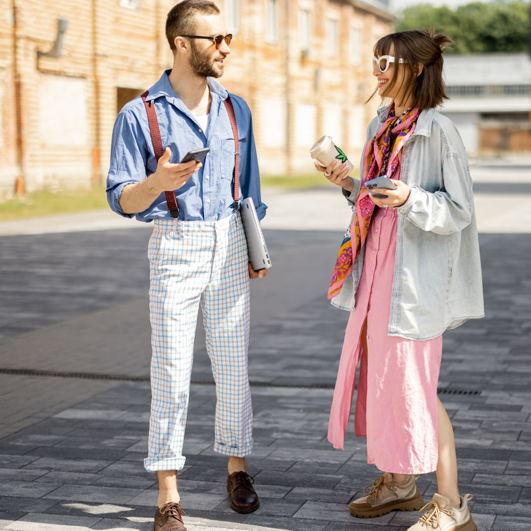 Two people walking on a sidewalk, one holding a phone and the other with a colorful scarf.