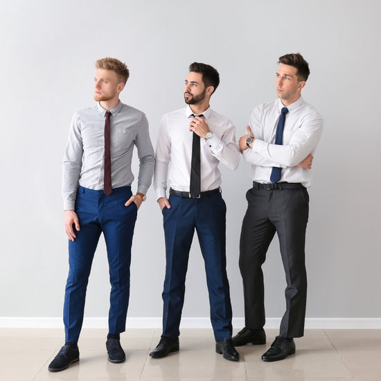 Three men in formal attire standing against a plain background