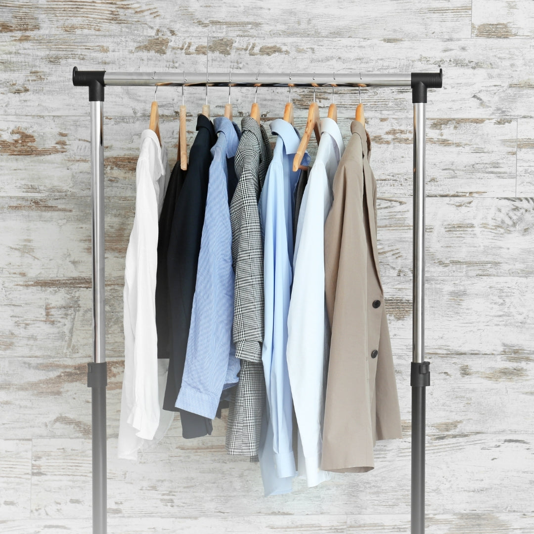 Clothing rack with various shirts and jackets against a textured wall.