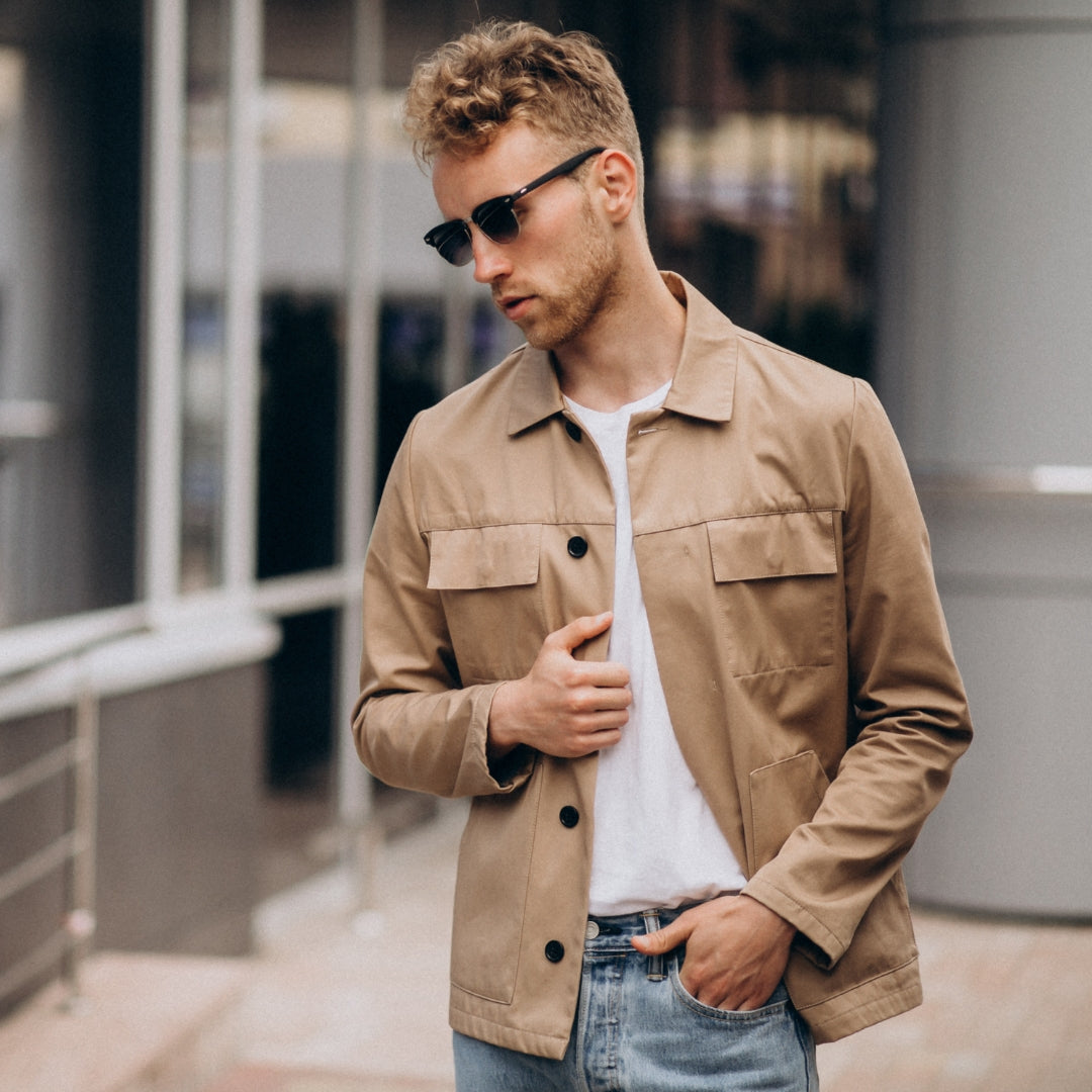 Man wearing a beige jacket and sunglasses in an urban setting