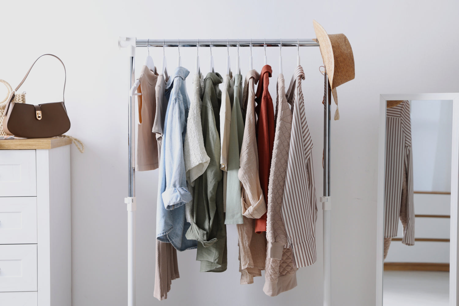 Organized clothing rack with neutral toned womens tops and accessories displayed