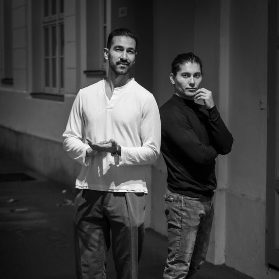 Two men standing against a building wall in a black and white photo.